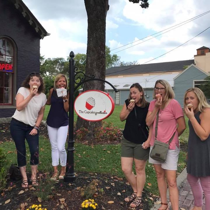 Group of ladies eating cupcakes outside the Cupcake Collection. The cupcakes have a pink frosting.