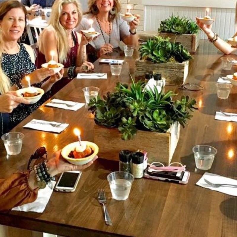 People at a table enjoying a cross between a donut and biscuit