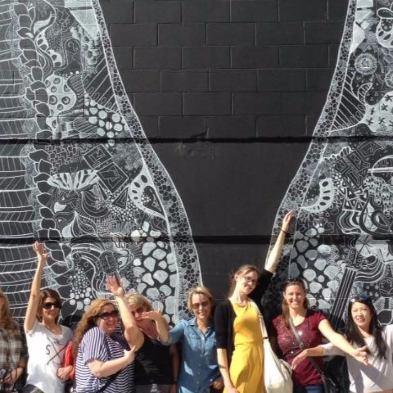 People enjoying a mural of intricate white outlined wings on a black wall