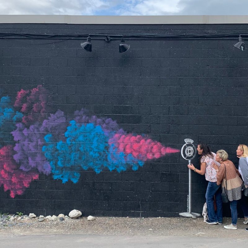 a group of people standing in front of a graffiti covered building