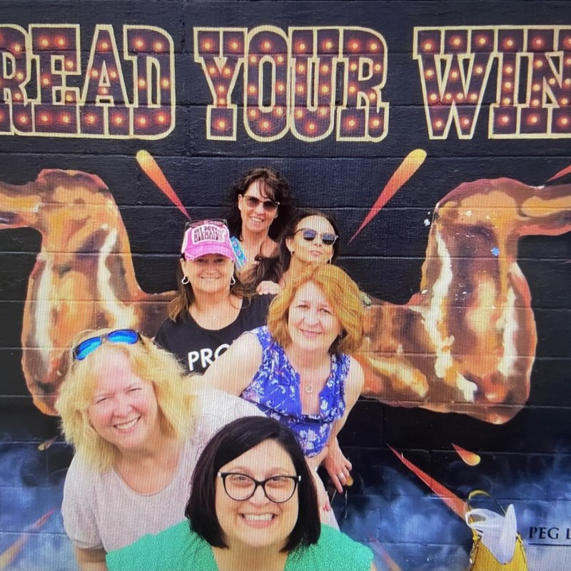 women posing in front of mural